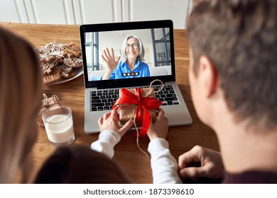 Happy family parents with kid child daughter holding Christmas gift greeting old senior grandparent on laptop screen having virtual party dinner on video conference call celebrating holiday together. - Powered by Shutterstock