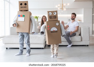 Happy family of parents and two children playing dancing like robots at home, children wearing handmade moving box costume of cardboard - Shutterstock ID 2018759225