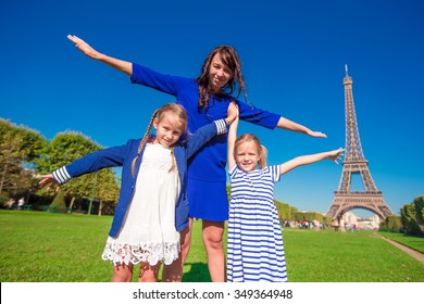 Happy Family In Paris Near Eiffel Tower. French Summer Holidays, Travel And People Concept.