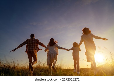 Happy family in the park. Father, mother and children are running, having fun and enjoying summer evening.