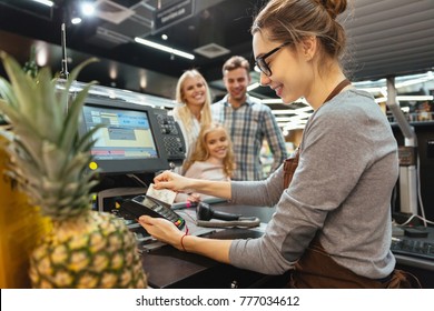 Happy family paying for their groceries with a credit card while standing at cash desk at the supermarket Stock Photo