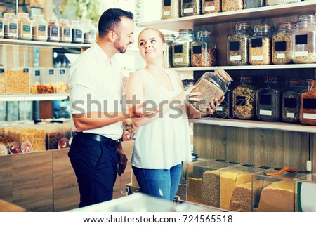 Happy family picking glass can with dried herbs in organic shop