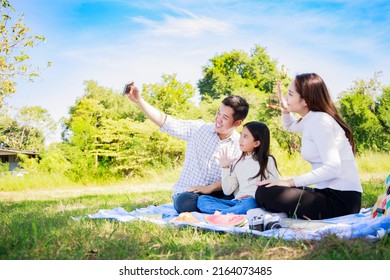 Happy family picnic. Asian parents, girl take a selfie by smartphone  together during picnic - Powered by Shutterstock