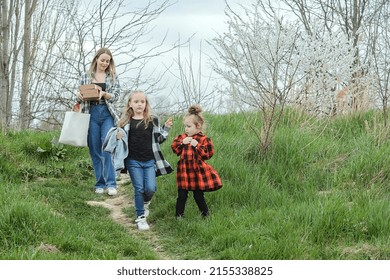 Happy Family Picnic In Early Spring Outside The City, Mom And Two Daughters Of Different Ages Go On A Picnic With Pizza Boxes