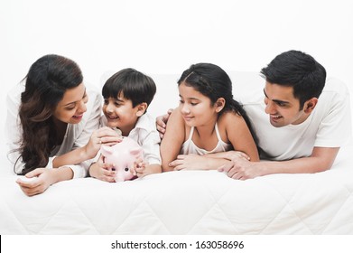 Happy Family With A Piggy Bank On The Bed