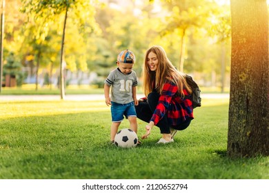 Happy family play football in summer, Mother and son play and run in the park on a beautiful morning. A boy kicks football while playing with his family. Family concept