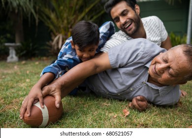 Happy family playing american football on field in yard
