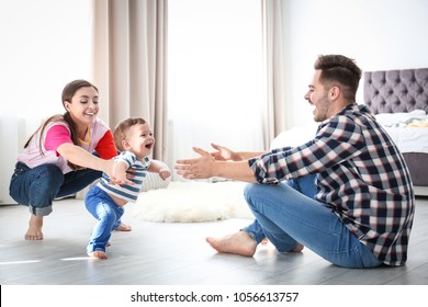 Happy Family Playing And Baby Learning To Walk At Home