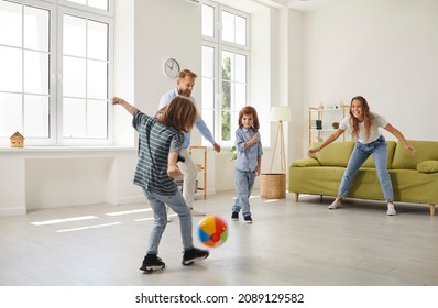 Happy Family Playing Ball Inside The House. Young Mother, Father And Little Children Playing Football With A Toy Ball At Home. Mommy, Daddy And Kids Playing Soccer And Having Lots Of Fun Together