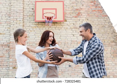 Happy Family Playing Basketball Together On Playground