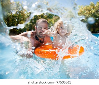 Happy Family Playing In Blue Water Of Swimming Pool On A Tropical Resort At The Sea. Focus On Children`s Hand And Splash, Shot Was Taken With Waterproof Box