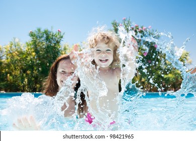 Happy Family Playing In Blue Water Of Swimming Pool On A Tropical Resort At The Sea. Summer Vacations Concept