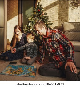 Happy Family Playing Board Game Walker At Home, Christmas Tree On Background. Holidays Home.