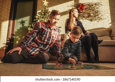 Happy Family Playing Board Game Walker At Home, Christmas Tree On Background. Holidays Home.