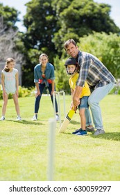 Happy Family Playing Cricket Together In Backyard