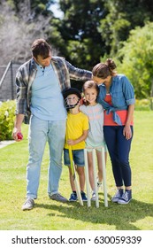 Happy Family Playing Cricket Together In Backyard