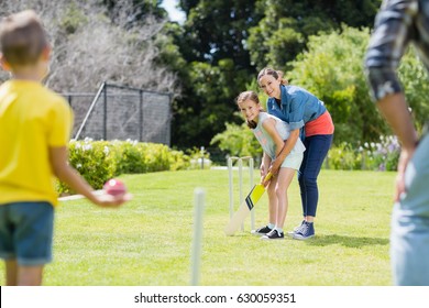 Happy Family Playing Cricket Together In Backyard