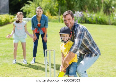 Happy family playing cricket together in backyard - Powered by Shutterstock