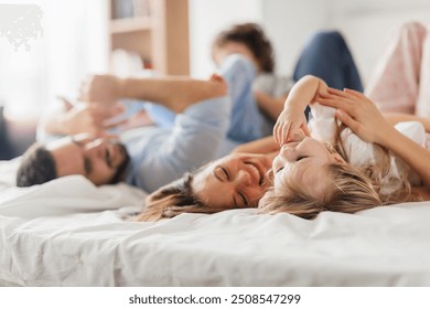 Happy family playing and laughing together on bed in the morning - Powered by Shutterstock