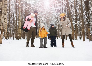 Happy Family Playing And Laughing In Winter Outdoors In Snow. City Park Winter Day.