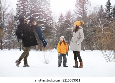 Happy Family Playing And Laughing In Winter Outdoors In Snow. City Park Winter Day.