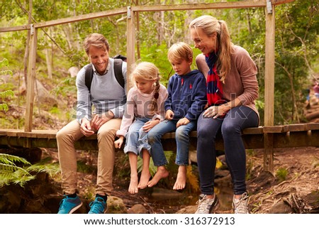 Happy family playing on a bridge in a forest, full length