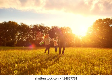 Happy Family Playing On The Grass In The Park In The Evening.