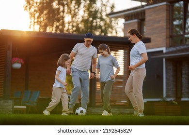 Happy family playing soccer. Young active people enjoying sunny summer evening outdoor. Healthy sport for kids. Football game club. - Powered by Shutterstock