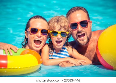 Happy Family Playing In Swimming Pool. Summer Vacation Concept