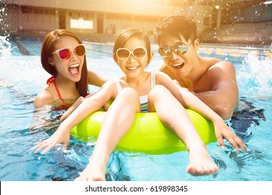 Happy family playing in swimming pool - Shutterstock ID 619898345