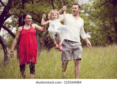 Happy Family Is Playing Together In A Green Meadow.