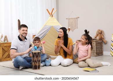 Happy family playing together near toy wigwam at home - Powered by Shutterstock