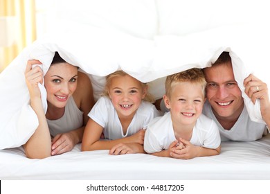 Happy family playing together on a bed at home