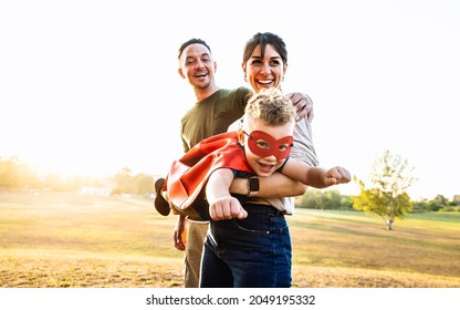 Happy Family Playing Together Outside - Kid In A Superhero Costume Having Fun With Mother And Dad In The Park At Sunset - Family, Love And Childhood Concept