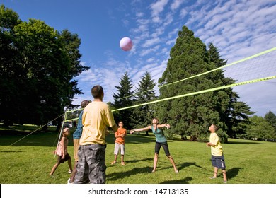A happy family, playing volleyball together outdoors. - horizontally framed