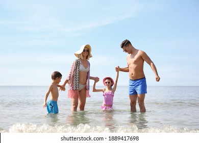 Happy Family Playing In Water At Beach On Sunny Day