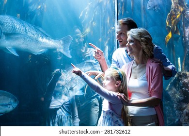 Happy family pointing a fish in the tank at the aquarium