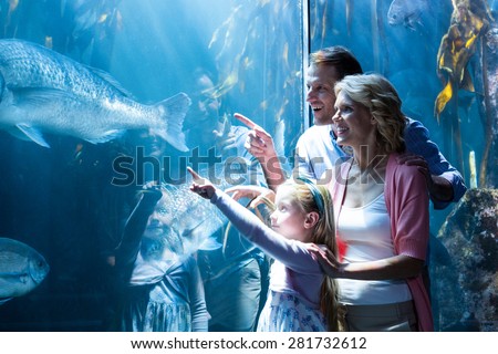 Happy family pointing a fish in the tank at the aquarium