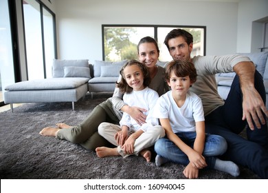 Happy Family Portrait At Home Sitting On Carpet