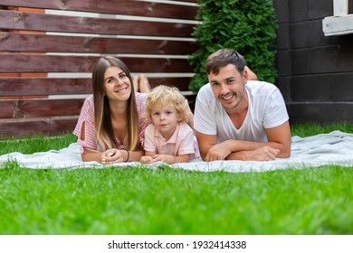 Happy Family Portrait On The Green Grass In The Yard Of Their House.