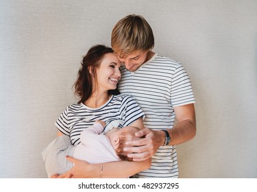 Happy family portrait - parents and their little cute baby girl. Mom breastfeeding newborn kid.