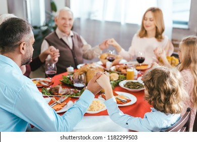 Happy Family Praying Before Thanksgiving Dinner At Home