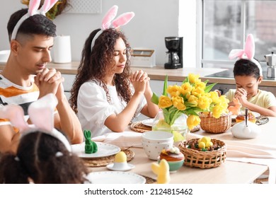 Happy Family Praying At Dining Table In Kitchen On Easter Day