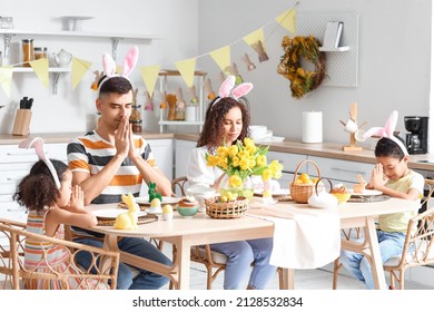 Happy Family Praying At Dining Table In Kitchen On Easter Day