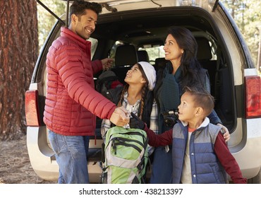Happy family prepare for a hike at the back of their car