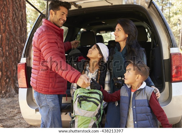 Happy\
family prepare for a hike at the back of their\
car
