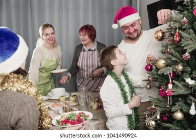 Happy family preparing for celebration of New Year, decorating Christmas tree and setting table