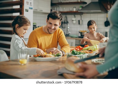 Happy family preparing dining table for lunch at home. Focus is on father.  - Shutterstock ID 1936793878
