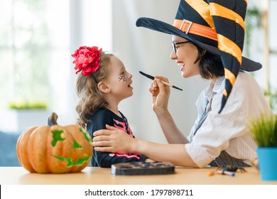 Happy Family Preparing For Halloween. Mother And Child In Carnival Costumes Doing Makeup At Home.