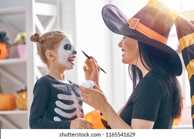 Happy Family Preparing For Halloween! Young Mom And Her Kid In Carnival Costumes Celebrate The Holidays.